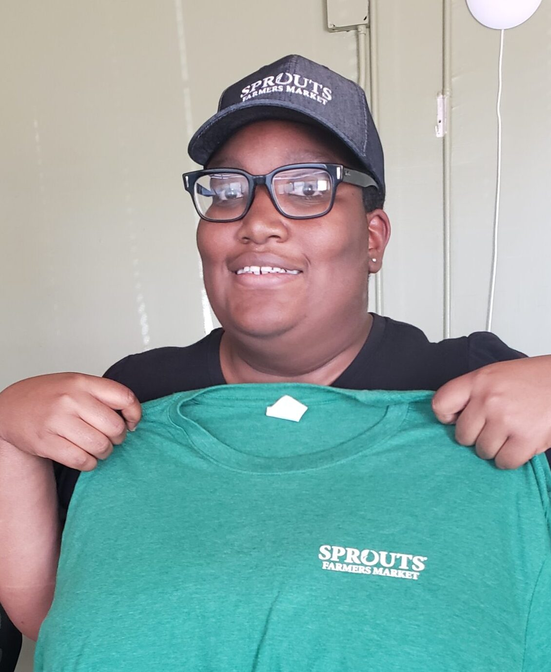 Janika, a Member of The Opportunity Tree's employment services program, smiles and poses with her uniform at Sprouts.
